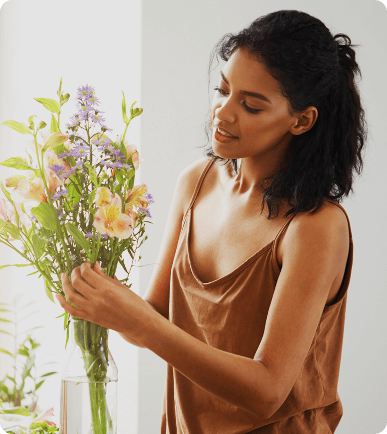 Woman arranging flowers in a vase indoors.